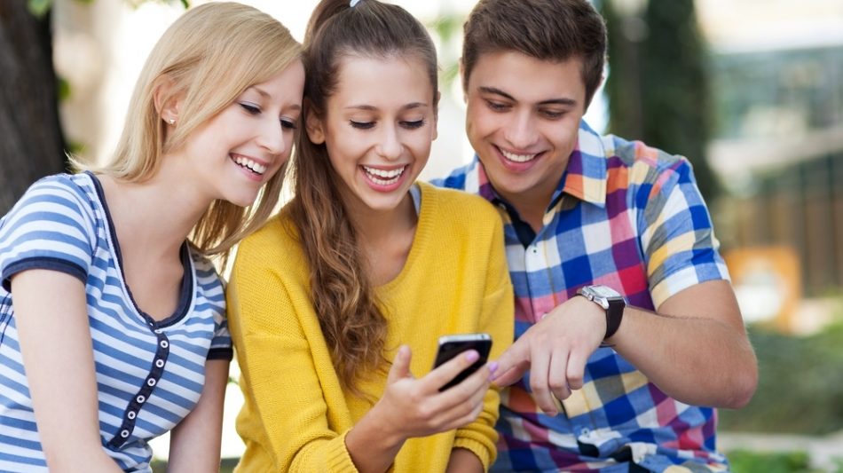 Drei junge Menschen schauen auf ein Handy