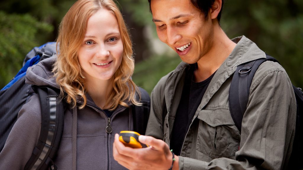 Frau und Mann mit einem GPS-Gerät beim Geocaching